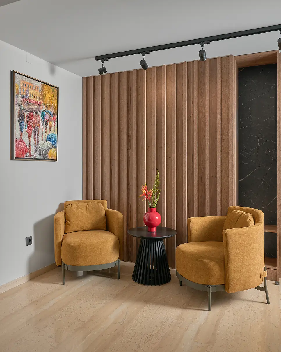 Εσωτερικό του γραφείου του δικηγόρου Γεώργιου Πιταροκοίλη, με δύο μονοθέσιους καναπέδες, τραπεζάκι με κόκκινο βάζο και φυτά, καθώς και πίνακα στον τοίχο